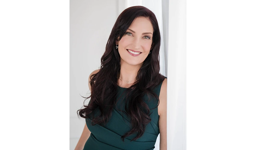 photo of a dark haired light skinned woman in a green dress looking at the camera